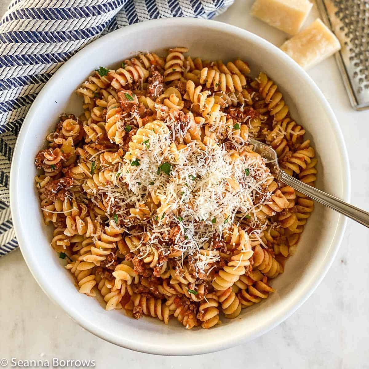 Delicious ground bison pasta in a white bowl with a fork.