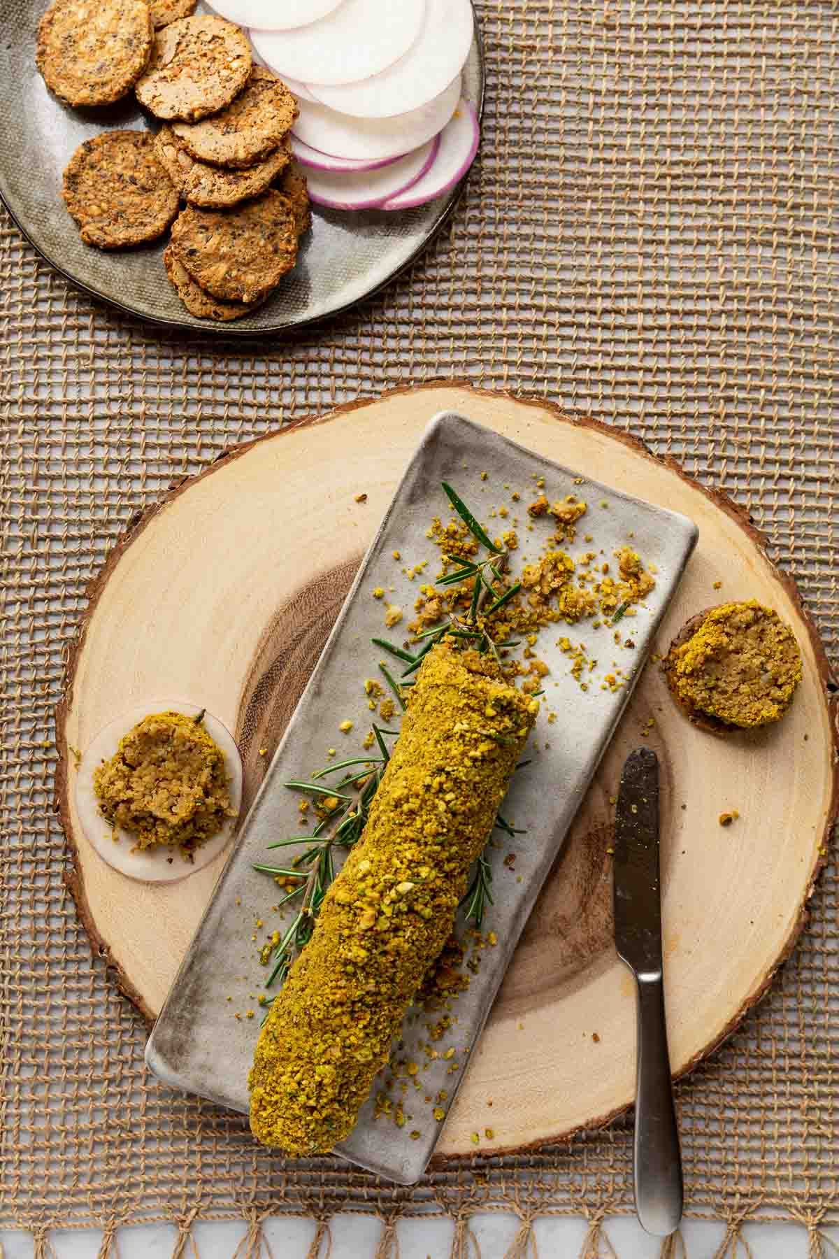 Scrumptious lemon rosemary vegan cheese log on a tray.