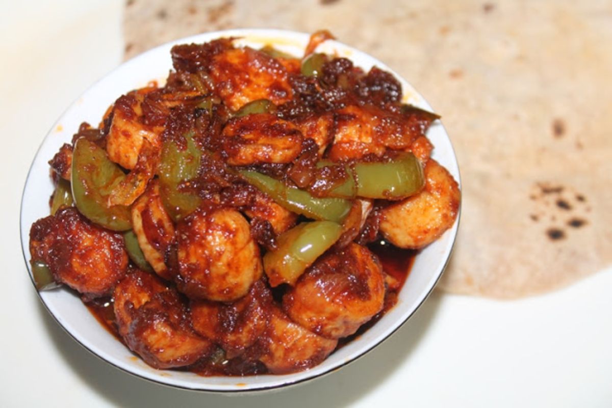 Juicy curry roasted chicken sausage and vegetables in a white bowl.