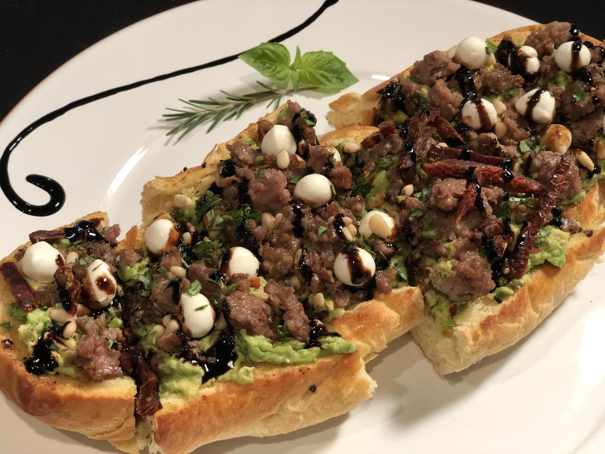 Flavorful avocado sausage garlic bread on a white plate.