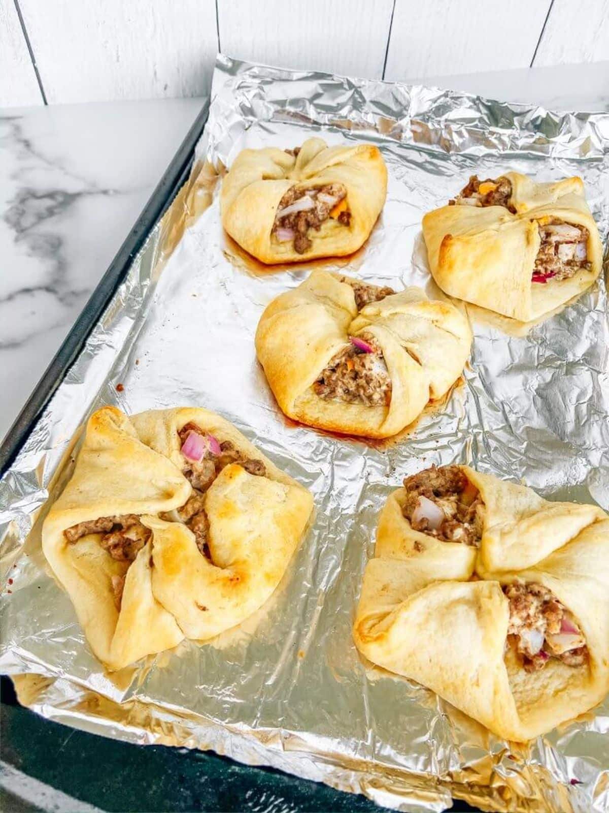 Tasty venison cream cheese stuffed crescent rollson a baking tray.