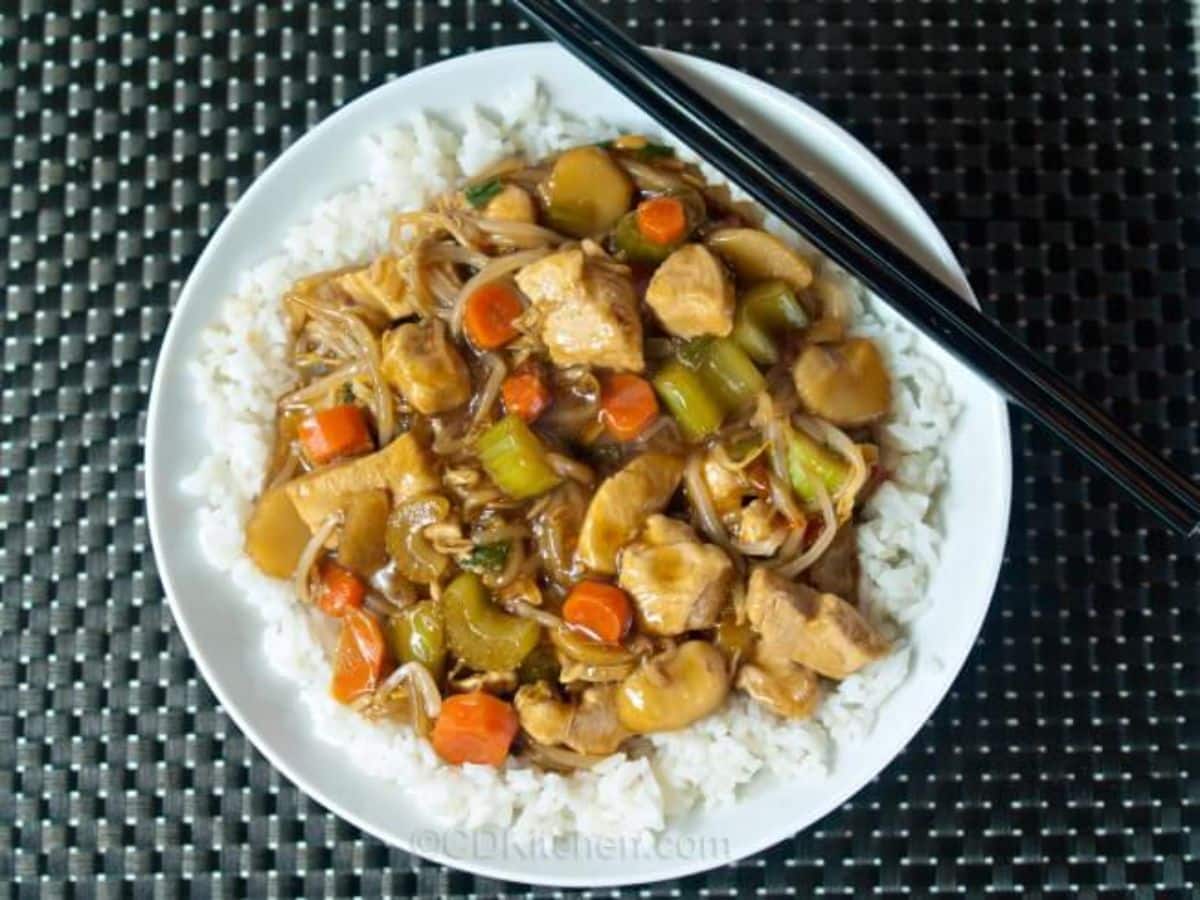 Scrumptious crockpot chicken chow mein with rice on a white plate with chopsticks.